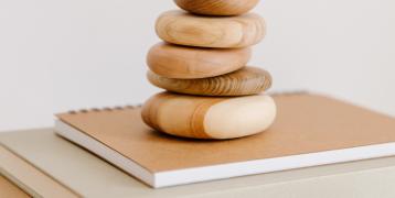 A number of wood-coloured stones above a book and notepaper